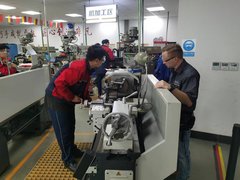Mitarbeiter des AZ Zwickau mit einem chinesischen Auszubildenden an einer Arbeitsmaschine.