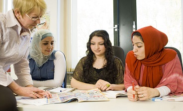Drei Migrantinnen lernen mit ihrer Seminarleiterin im Deutschkurs