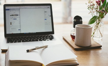 Laptop mit Buch und Kaffeetasse