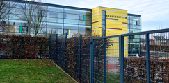 Modernes Schulgebäude mit Glasfassade und gelb verkleideter Front, beschriftet mit „Schulzentrum Stadt Könnern“.