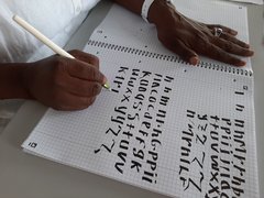 Eine Frau schreibt Buchstaben mit einem speziellen Kalligraphiestift