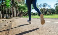 Dargestellt ist eine Person beim Joggen in einem Park. Man sieht nur ihre Beine.