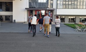 6 Jugendliche laufen auf den Eingang des Bauhauses in Dessau zu. Sie wurden von hinten fotografiert.