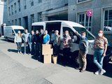 Galeriebild: Elf Personen mit Mundschutz stehen mit Kartons vor einem Transporter