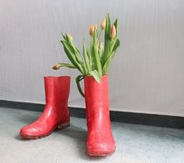 Rote Gummistiefel, einer mit Tulpen gefüllt