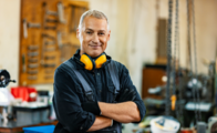 Ein Mann steht in der Werkstatt und schaut zufrieden in die Kamera.