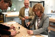 2 Besucher*innen probieren sich unter Anleitung einer Mitarbeiterin im Berufsfeld Holz aus