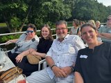 Foto von der Schifffahrt. Mehrere Teilnehmende sitzend auf dem Oberdeck. 