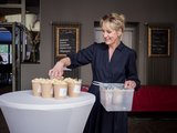 Fachtagung Depression Foto: Eine Frau stellt mit Popcorn gefüllte und dem faw-btz-Logo versehene Becher auf einen Stehtisch