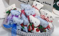 Ein gehäkelter grauer Korb ist gefüllt mit genähten blauen und weißen Teddybären. Jeder Teddy hat eine Schleife um den Hals.