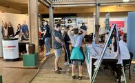 Links steht ein Jugendlicher am Stand von Ernsting's Family. Rechts informiert sich ein Vater mit seiner Tochter und seinem Sohn am Stand von pino Küchen.
