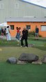 Sommerfest 2026 Mitarbeiterin puttet erfolgreich beim Minigolf. Im Hintergund sind weitere Mitarbeiter und das Gebäude des Sportpark Cottbus zu sehen.