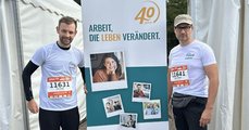 Die Zwei mit Durchstarterticket Foto: Zwei Kollegen mit Ticket für schnellen Läufer vor dem Roll-up „40 Jahre faw“