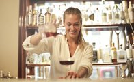 Eine Frau an der Bar gießt ein Getränk ein.