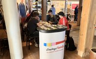 Zwei junge Männer sitzen am Stand von Ernsting's Family und unterhalten sich mit einer Mitarbeiterin und einem Mitarbeiter des Unternehmens.