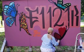 Junge Frau arbeitet an einem Graffiti an rosafarbener Wand