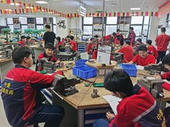 Blick in die chinesische Ausbildungsstätte. Mehrere Auszubildende an Werkbänken. 