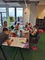 Foto: Kinder und ihr Betreuer beim Basteln und Zeichnen rund um einen Tisch.