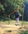 Zwischen zwei Pfosten ist eine Latte schräg angebracht. An der niedrigsten Stelle ist sie 1,50 Meter hoch, an der höchsten 3 Meter. An dieser Hochsprunglatte springt ein Auszubildender mit Rucksack bei 2,80 Meter nach oben. Er hat die Hand ausgestreckt, um gegen die Latte zu schlagen.