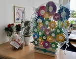 40 Jahre faw und 25 Jahre faw in Cottbus Nahaufnahme vom feierlich gestalteten Korb mit Papierblumen. Daneben Präsente einiger Netzwerkpartner und Kostenträger.
