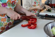 Foto: Eine Teilnehmende des Kompakt Stufenmodelles beim Paprikaschneiden im Rahmen der Berufsfelderkundung Küche.