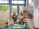 Foto: Zwei Mitarbeiterinnen der faw stehen am Messestand vor den beiden Roll-Ups.