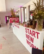 Fotografiert wurde der Eingang des HR Campus Mitteldeutschland. Auf einem weißen Tresen stehen Pflanzen, Getränke und eine Ananas.