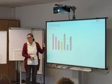 Foto: Anja Pieper, Referentin zum Thema Neurodiversität steht neben einem Smartboard und erklärt ein Schaubild