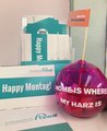 In einem Kartenständer stehen mehrere "Happy Montag"-Postkarten der FAW. Daneben steht eine pinke Kugel mit der Aufschrift "Home is where my Harz is".