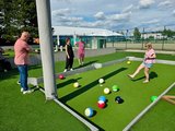 Sommerfest 2026 Eine Mitarbeiterin spielt Fußball-Billard. Am Rand stehen drei weitere Mitarbeiter und schauen zu.