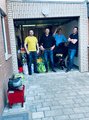 Galeriebild: Vier junge Männer stehen mit Sachspenden in einer Garage.