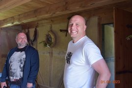 Zwei Männer stehen lachend in einem Bauernhaus