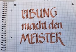 Ein Block mit den Worten „Übung macht den Meister“ in Kalligrafie