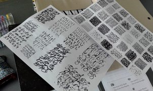 Buchstaben in Schönschrift und geschwungene Linien auf Papier