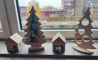 Foto: Zwei Weihnachtsbäume und zwei kleine Häuser als Holz stehen nebeneinander auf einem Fensterbrett.