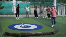 Sommerfest 2026 Mitarbeiterin trifft die Mitte beim Fußball-Curling. Die anderen Mitarbeiter schauen zu.