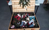 Foto: Eine große Holzkiste gefüllt mit genähten Nikolausstiefeln und dekorativen Tannenzweigen.