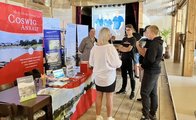 Drei Schüler stehen am Stand der Stadt Coswig (Anhalt) und unterhalten sich mit zwei Mitarbeiterinnen.