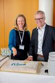 RehaDialog der faw in Köln Anja Hultsch & Björn Hagen schneiden einen Kuchen mit dem Jubiläumslogo der faw an