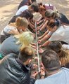 Die Auszubildenden balancieren einen Zollstock weniger Zentimeter über dem Boden auf ihren ausgestreckten Zeigefingern.