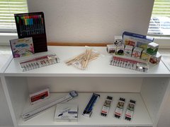 Stifte, Tinte und weiteres Schreibzubehör stehen in einem Regal