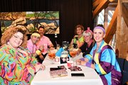 80er Jahre Party! Foto von der 80er Jahre Party: An einem Tisch sitzen sich fröhliche, im 80er Jahre Stil angezogene, Menschen gegenüber.