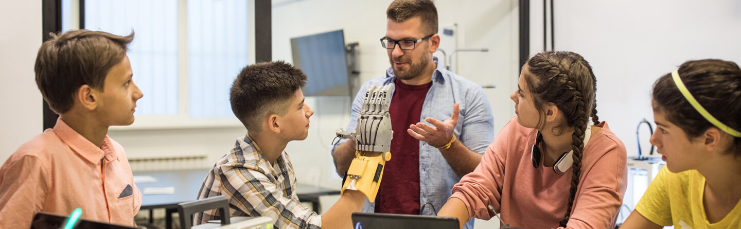 Inhaltsbild: Schülergruppe mit Lehrer erleben Künstliche Intelligenz am Beispiel eines computergesteuerten Handmodells.