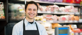 Ein männlicher Verkäufer arbeitet an einer Frischetheke - Symbolbild Verkauf