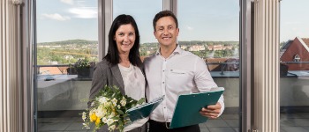 Zwei Personen mit Blumen und Mappe nach erfolgreichem Prüfungsabschluss