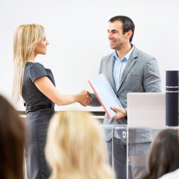 Ein Mann überreicht einer Frau mit einem Händeschütteln ein Zertifikat: Symbolbild Umschulung