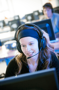 Junge Frau mit Headset am PC lernt im Blended-Learning-Format.
