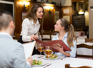 Eine Servicekraft berät einen Gast im Restaurant