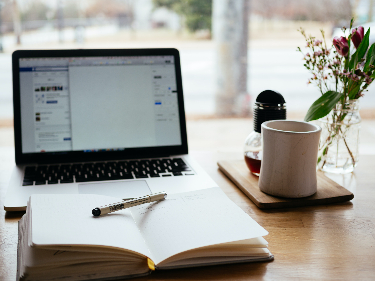 Laptop mit Buch und Kaffeetasse