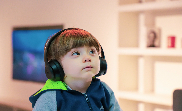 Ein kleiner Junge mit Trisomie 13 hört konzentriert etwas über Kopfhörer an.